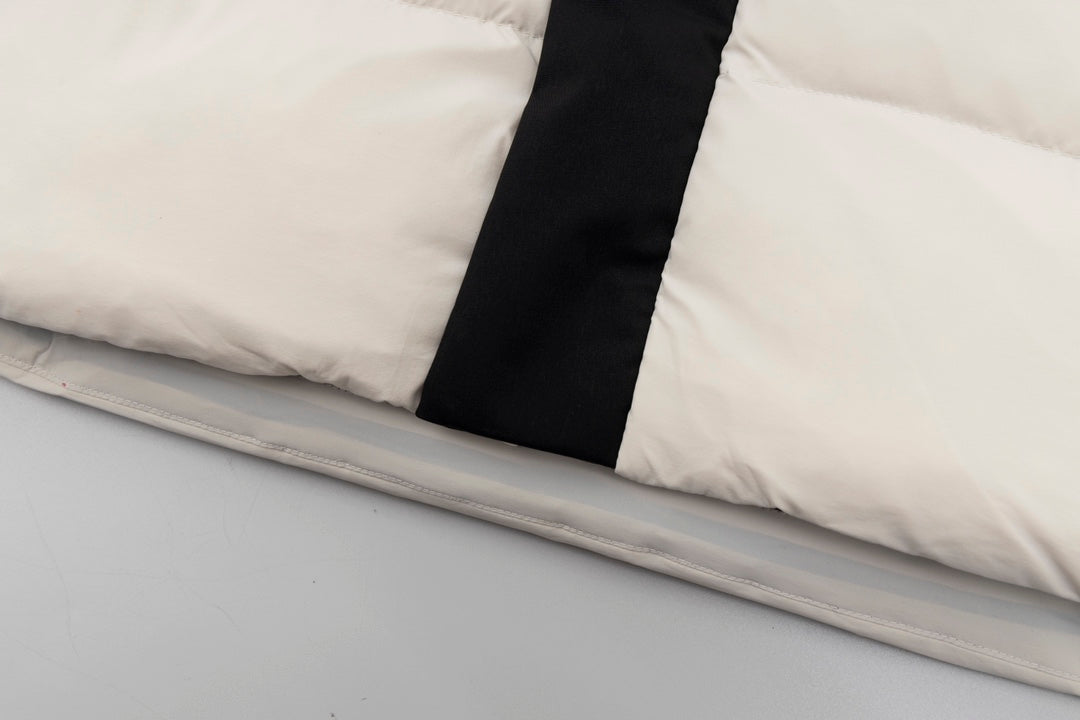 Cream puffer jacket hem with black center placket and stitched trim edge.