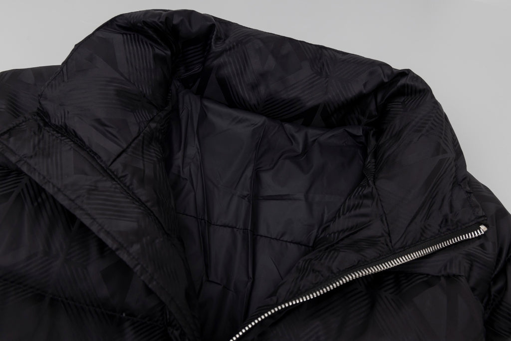 Black long puffer jacket close-up of side zipper and quilted fabric texture.