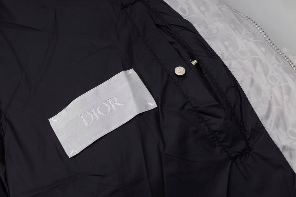 Black long puffer jacket shoulder detail with small button and Dior label.