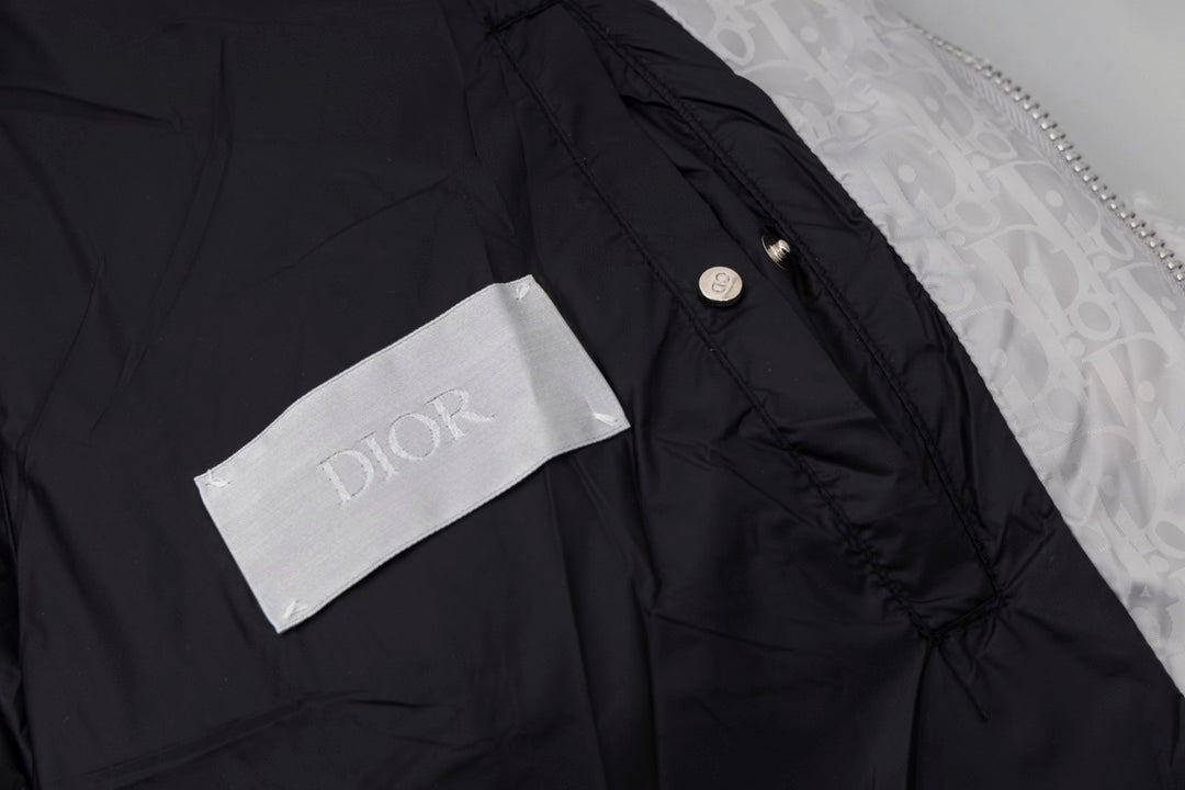 Black long puffer jacket shoulder detail with small button and Dior label.