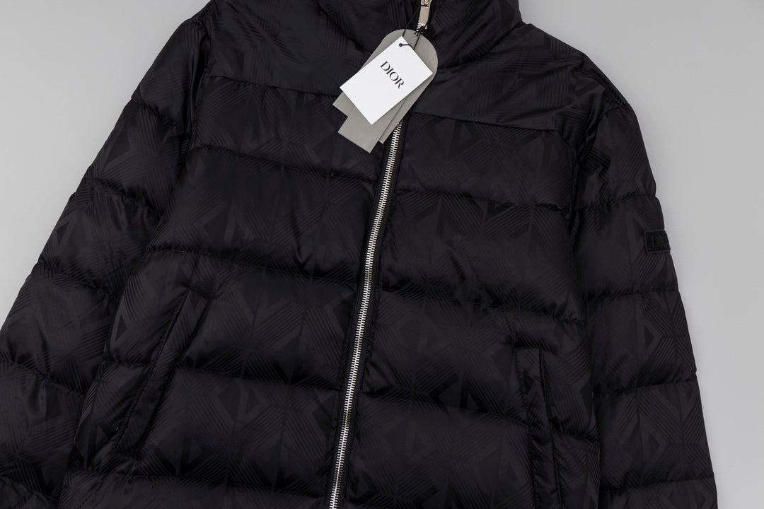 Black long puffer jacket close-up with front zipper and quilted panels.
