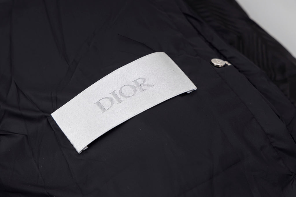 Black long puffer jacket with Dior logo fabric label on the chest.