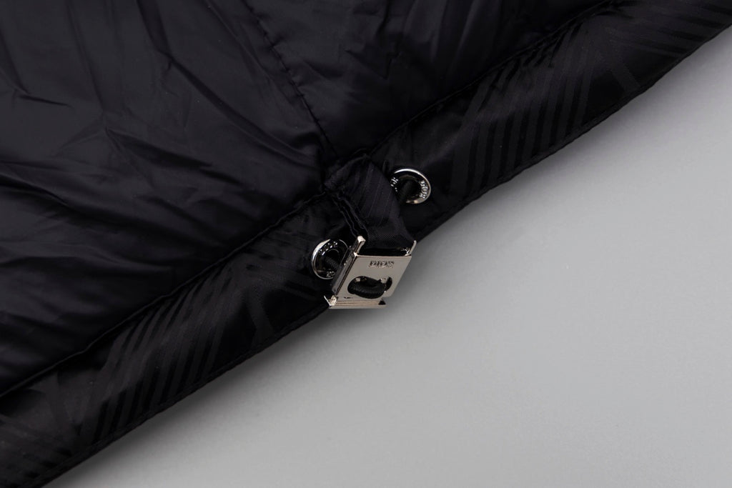Black long puffer jacket cuff close-up with snap button and zipper hardware.