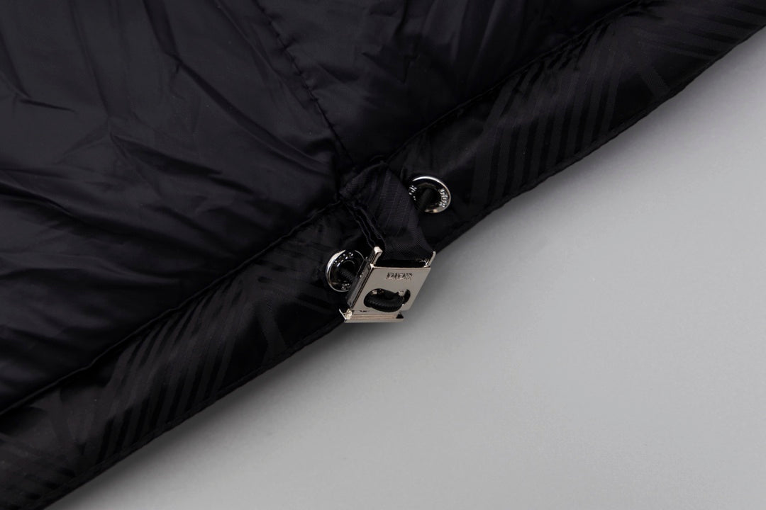 Black long puffer jacket cuff close-up with snap button and zipper hardware.