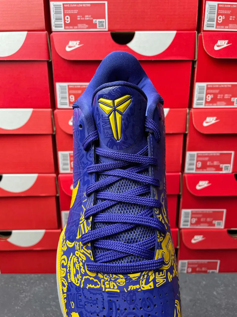 Blue basketball sneaker top view with yellow emblem on the tongue and laces