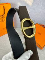 Dark leather belt with gold-tone double H buckle, close-up.