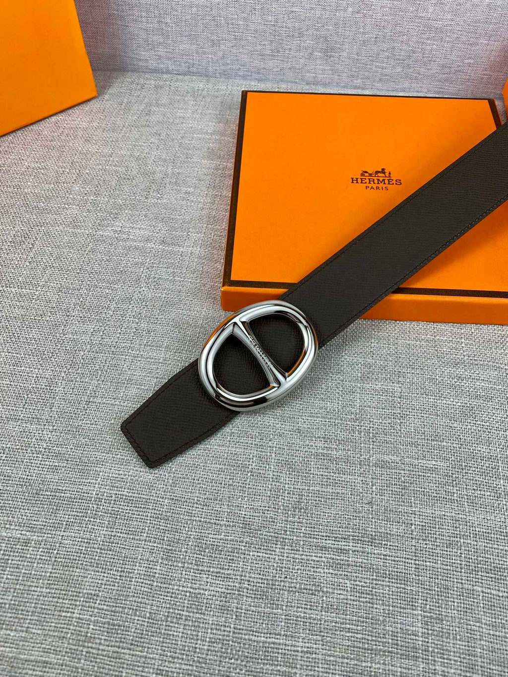 Dark leather belt with silver-tone double H buckle, belt end visible.