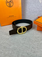 Dark leather belt with gold-tone double H buckle, laid flat.