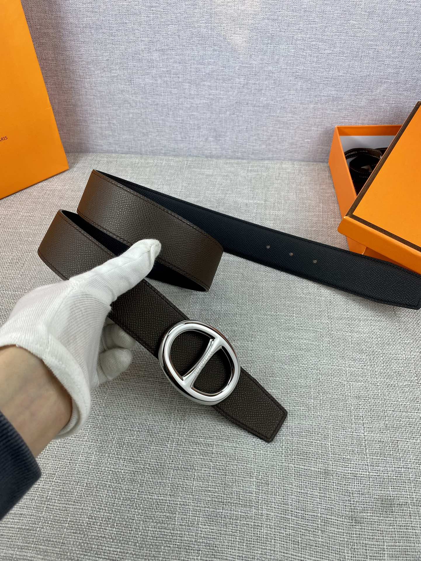 Dark leather belt with silver-tone double H buckle, strap and buckle detail.