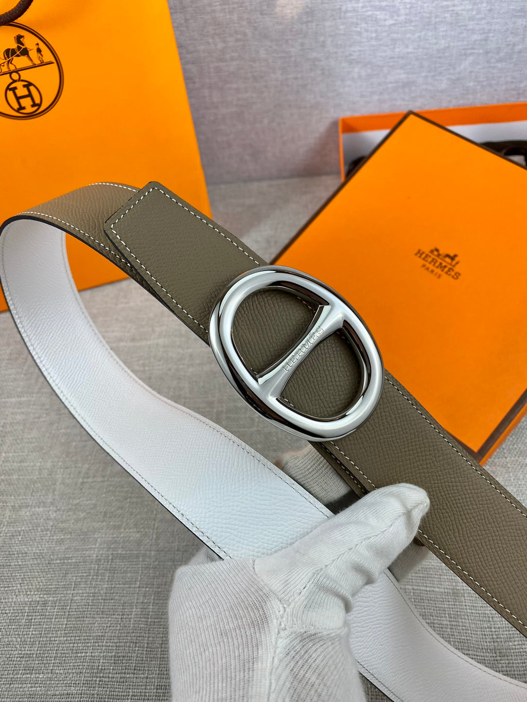 Olive leather belt with silver double-ring buckle and white strap underside