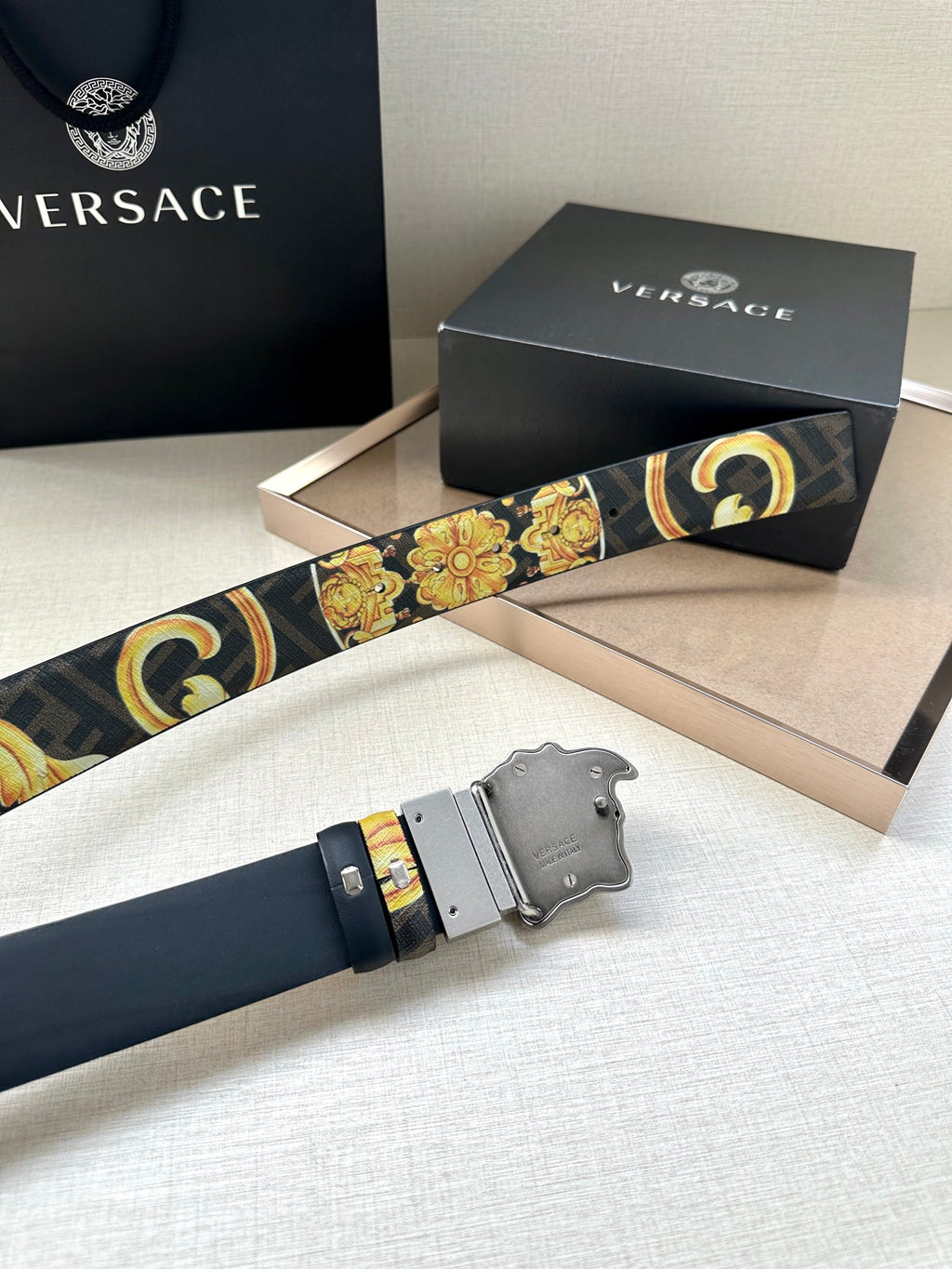 Versace belt detail: baroque gold-and-blue strap with dark buckle and gold trim.