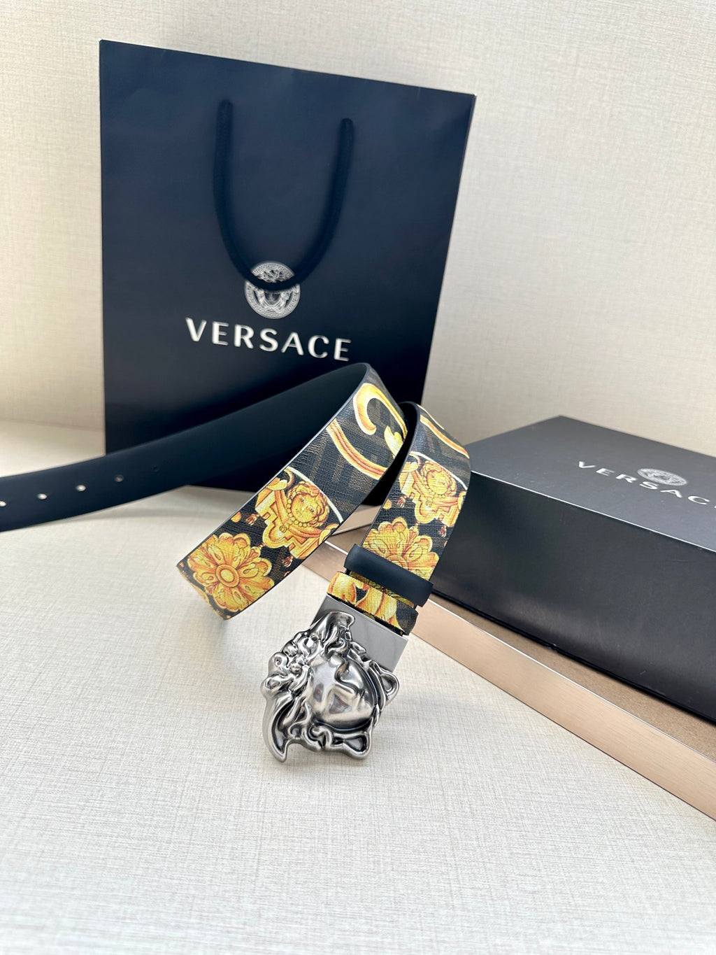 Versace belt with dark blue strap, baroque print, and ornate gold Medusa buckle.