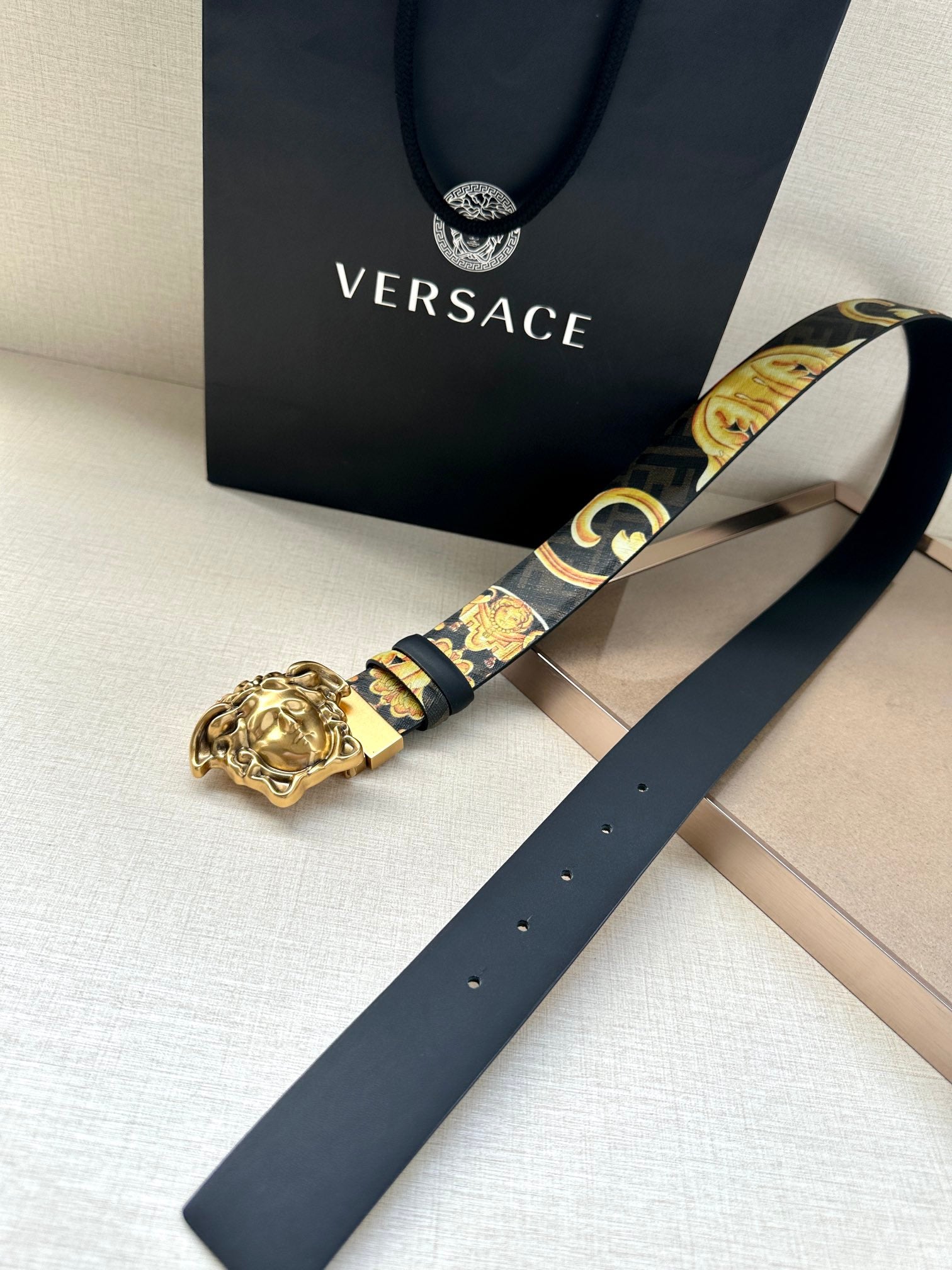 Versace belt detail: dark blue strap with baroque gold print and gold Medusa buckle.