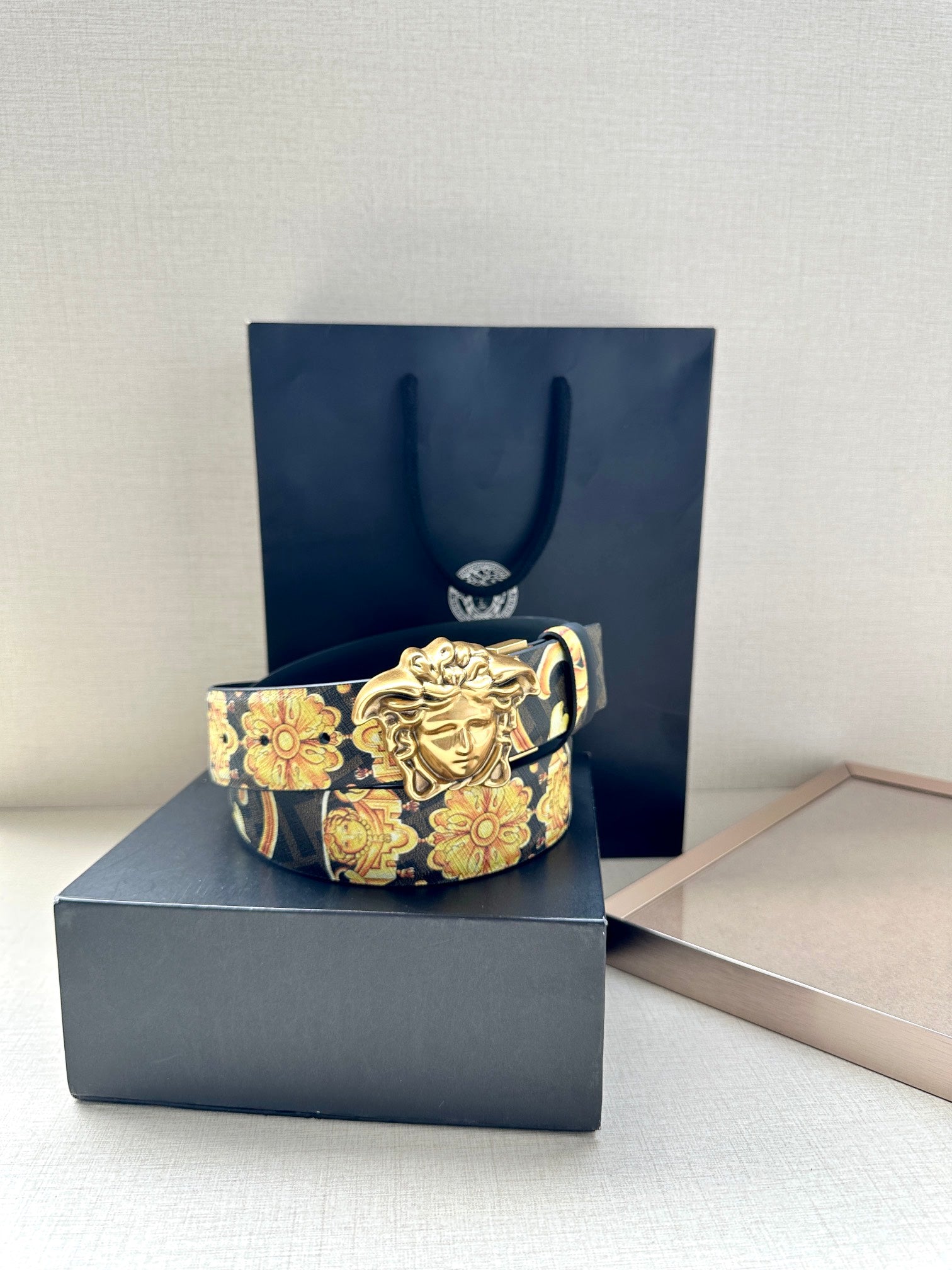 Versace belt featuring gold Medusa buckle with dark blue and gold patterned strap.