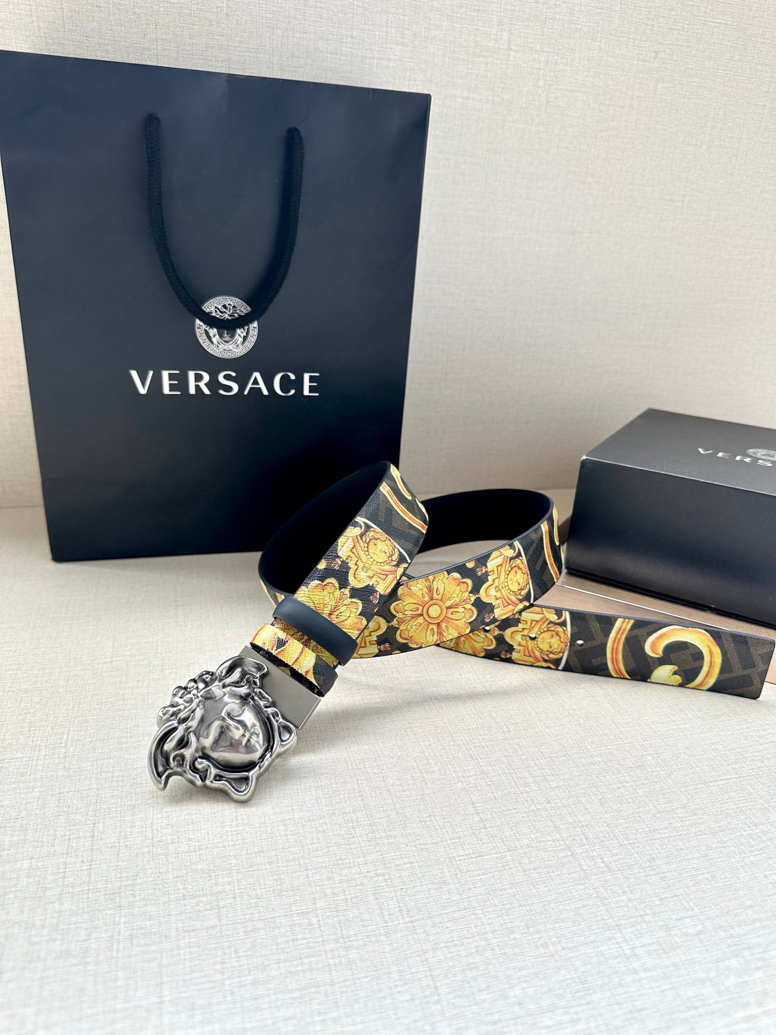 Versace belt with dark blue strap, baroque gold pattern, and silver-toned Medusa buckle.