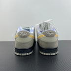 Grey suede sneakers with white laces, yellow swoosh, and black heel panels