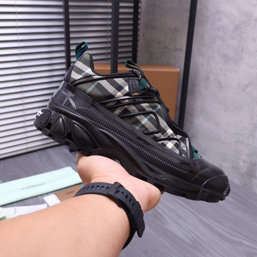 Burberry chunky sneakers, black with plaid panel and teal lace details, on hand view