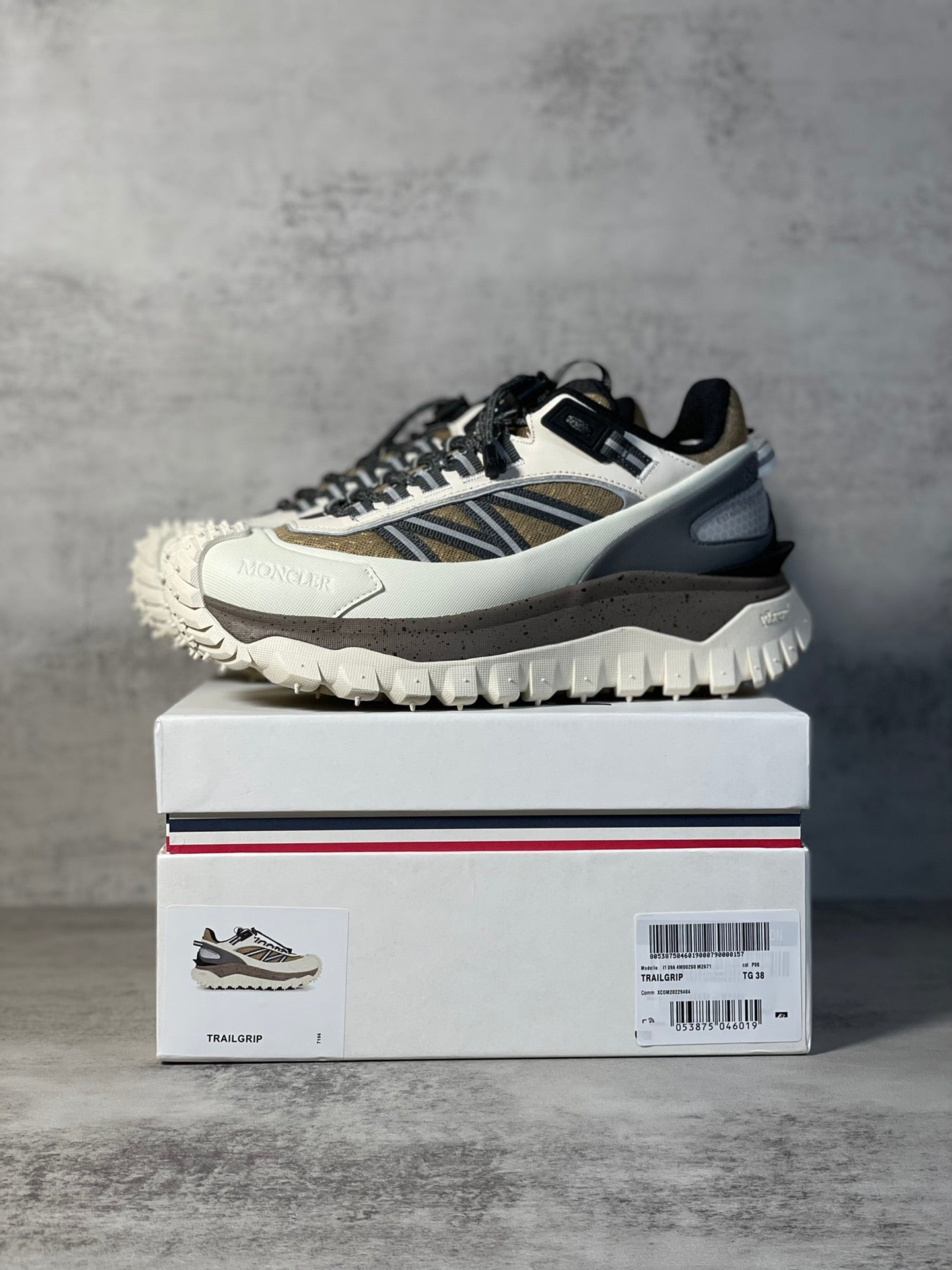 Moncler trail sneaker on shoebox, white upper with navy stripe and black laces