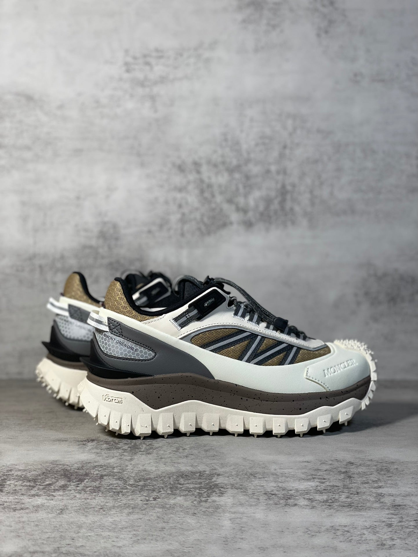 Moncler trail sneaker, angled view, white upper with navy stripe and black accents