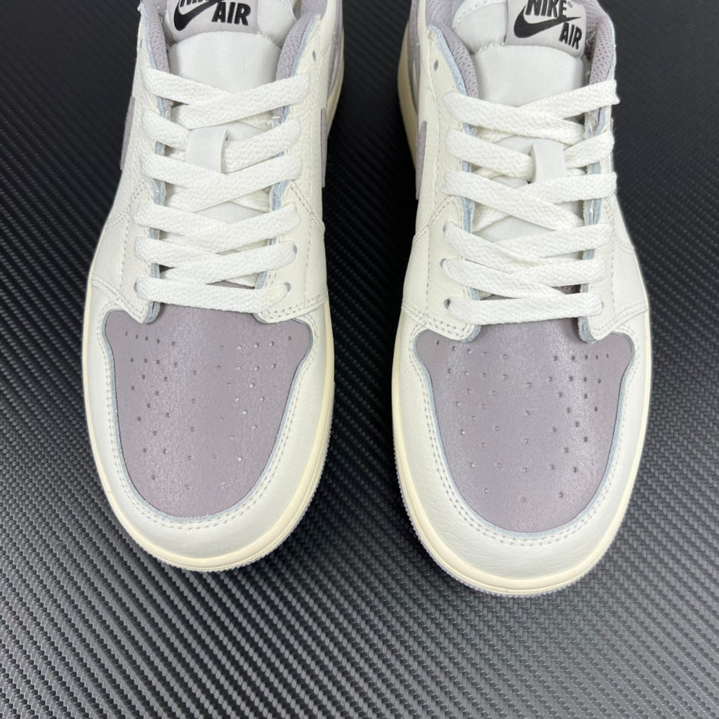 Front view of white low-top sneakers with perforated toe and lavender-gray overlays.