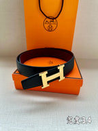 Leather belt with dark strap and gold-tone H buckle on orange box