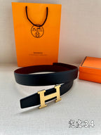 Leather belt with dark strap and gold-tone H buckle, laid flat