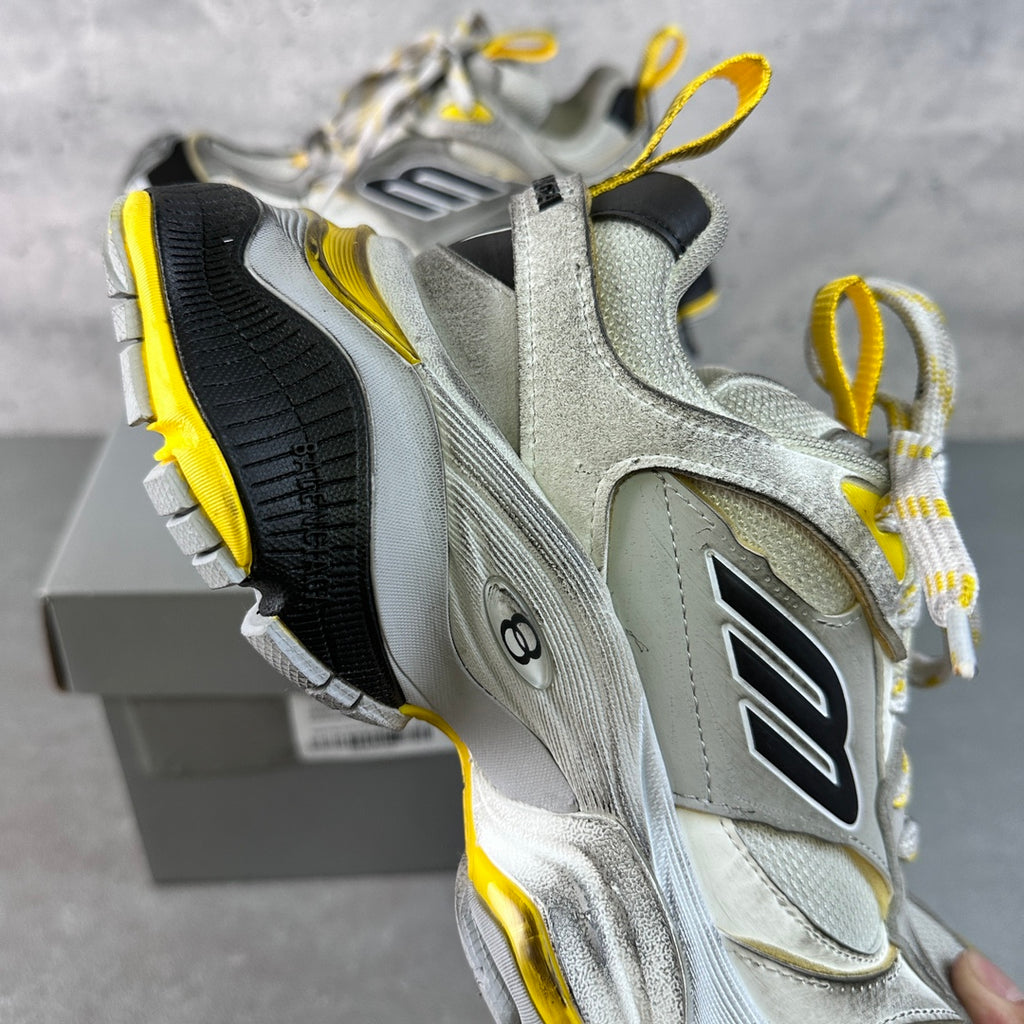 Balenciaga unisex sneakers showing side profile, silver-gray upper with black heel and yellow trim