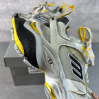 Balenciaga unisex sneakers showing side profile, silver-gray upper with black heel and yellow trim