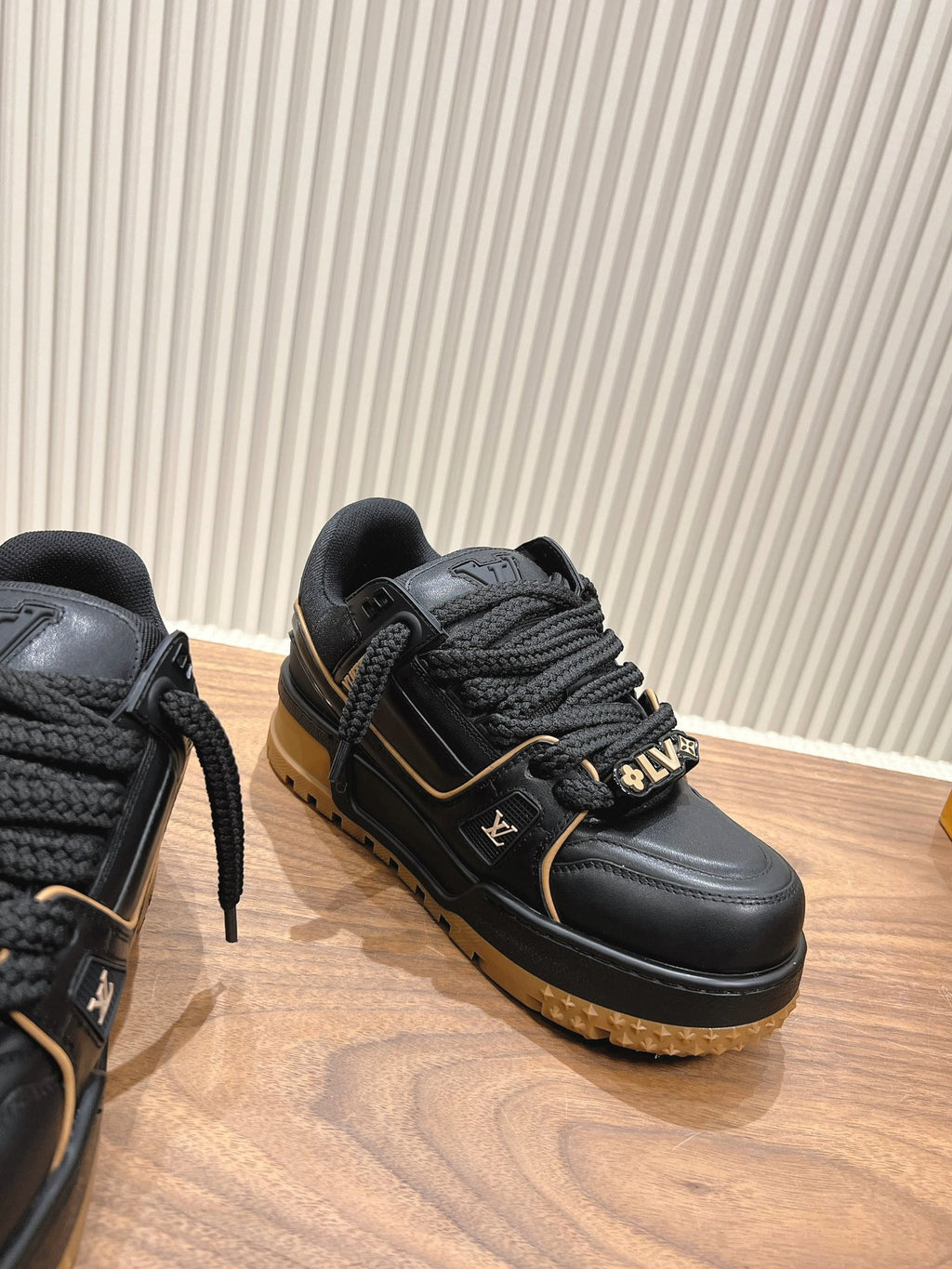 Black trainer sneaker with braided laces, gold trim and LV side emblem, tan sole