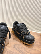 Black trainer sneaker with braided laces, gold trim and LV side emblem, tan sole
