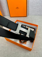 Black leather belt with silver-toned H buckle, shown inside an orange gift box