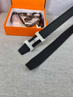 Black leather belt with silver-toned H buckle laid flat