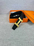Black leather belt with gold-toned H buckle, partially in an orange box
