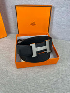 Black leather belt with silver-toned H buckle in an open orange box
