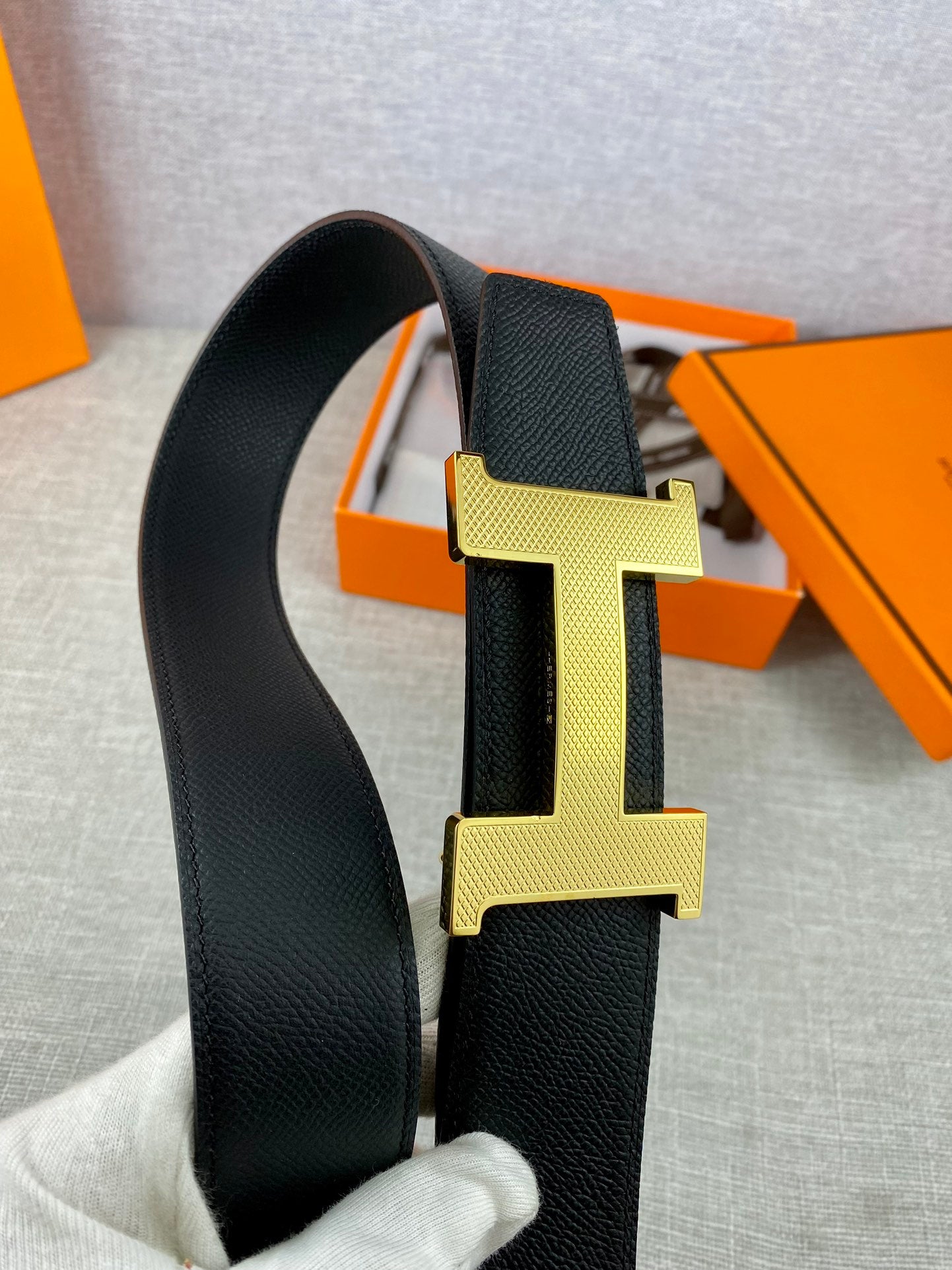 Black leather belt showing gold-toned H buckle detail