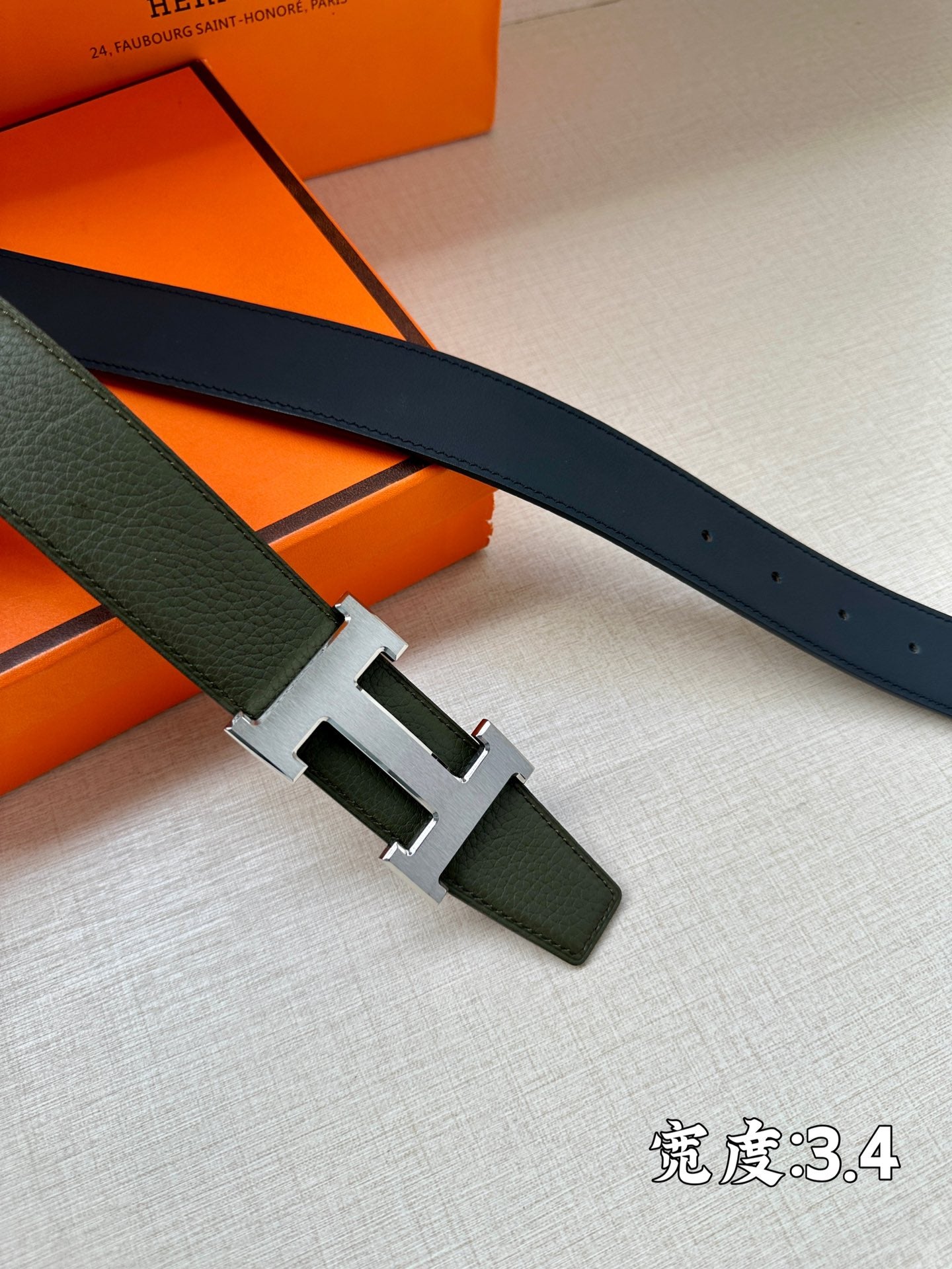 Green leather belt with silver-toned H buckle and punched holes
