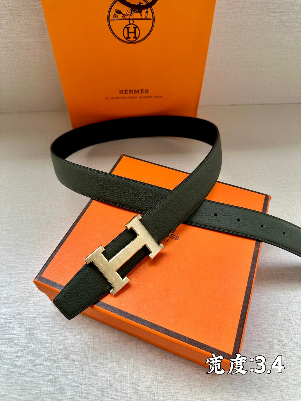 Green leather belt with gold-tone H buckle, angled front view