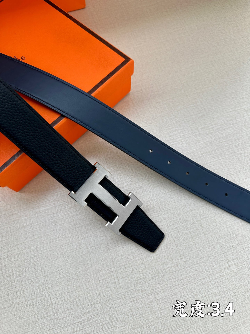 Hermes belt end and buckle detail in dark blue leather with gold-tone H