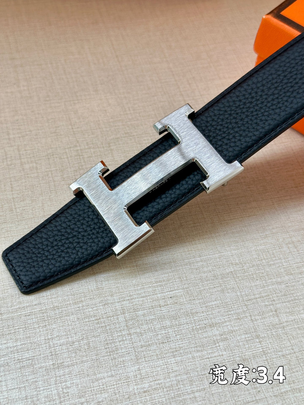 Hermes belt buckle close-up: gold-tone H with dark blue strap