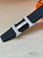 Hermes belt buckle close-up: gold-tone H with dark blue strap