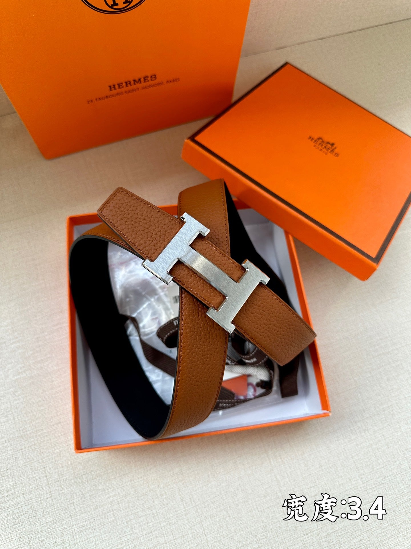Brown leather belt with silver H buckle, shown in packaging