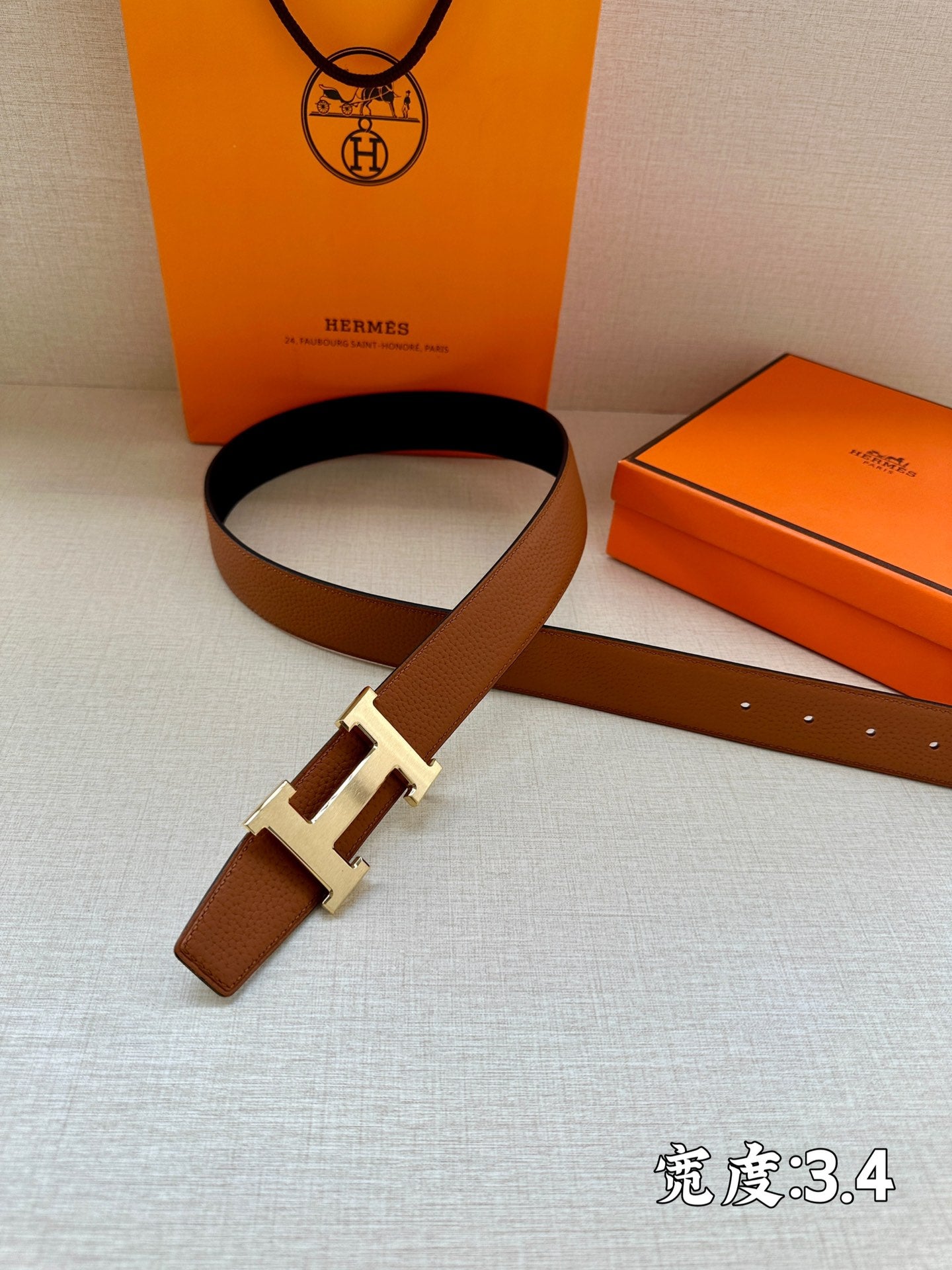 Brown leather belt with silver H buckle, laid flat
