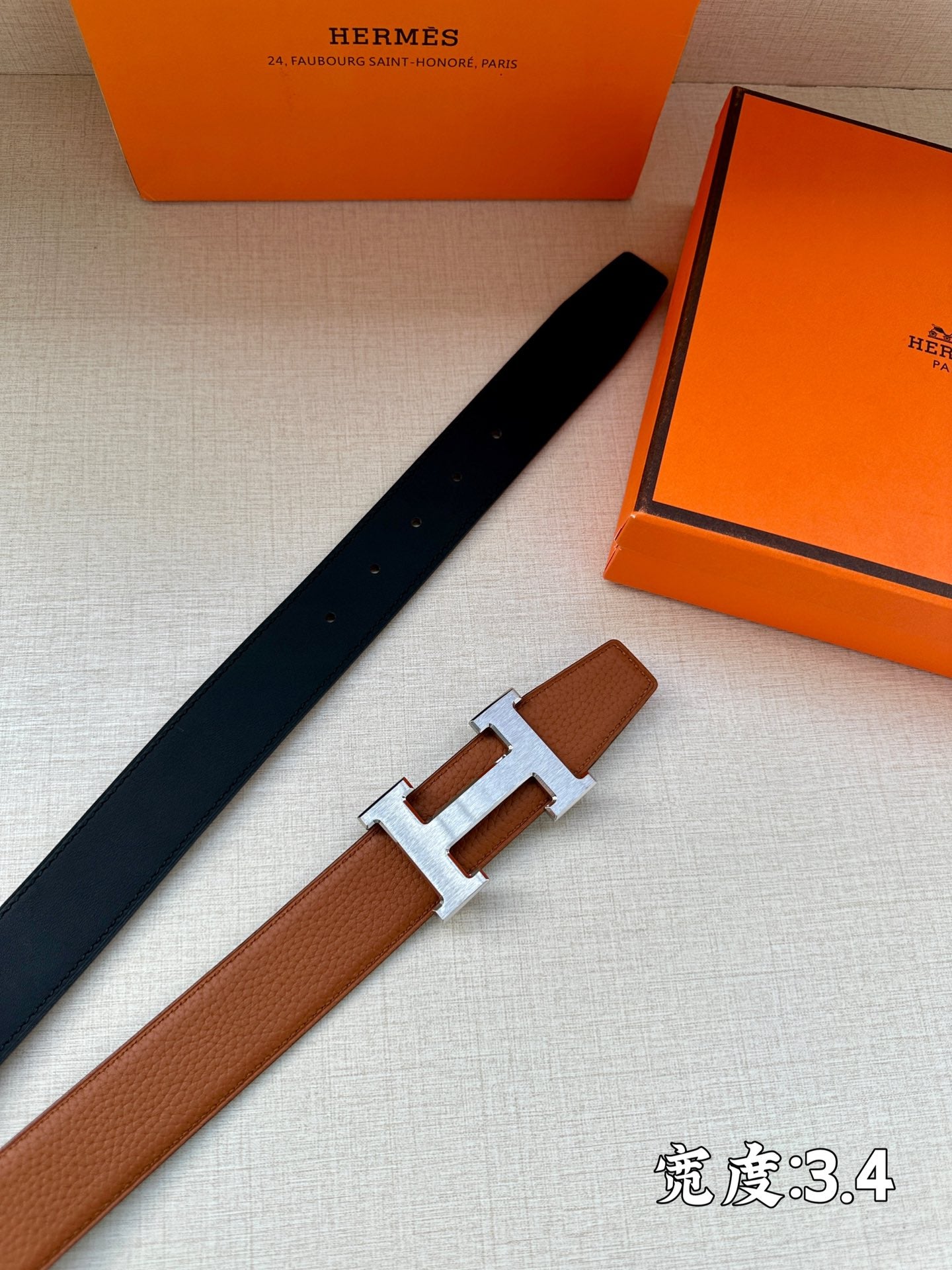 Navy leather belt with silver H buckle, laid diagonally