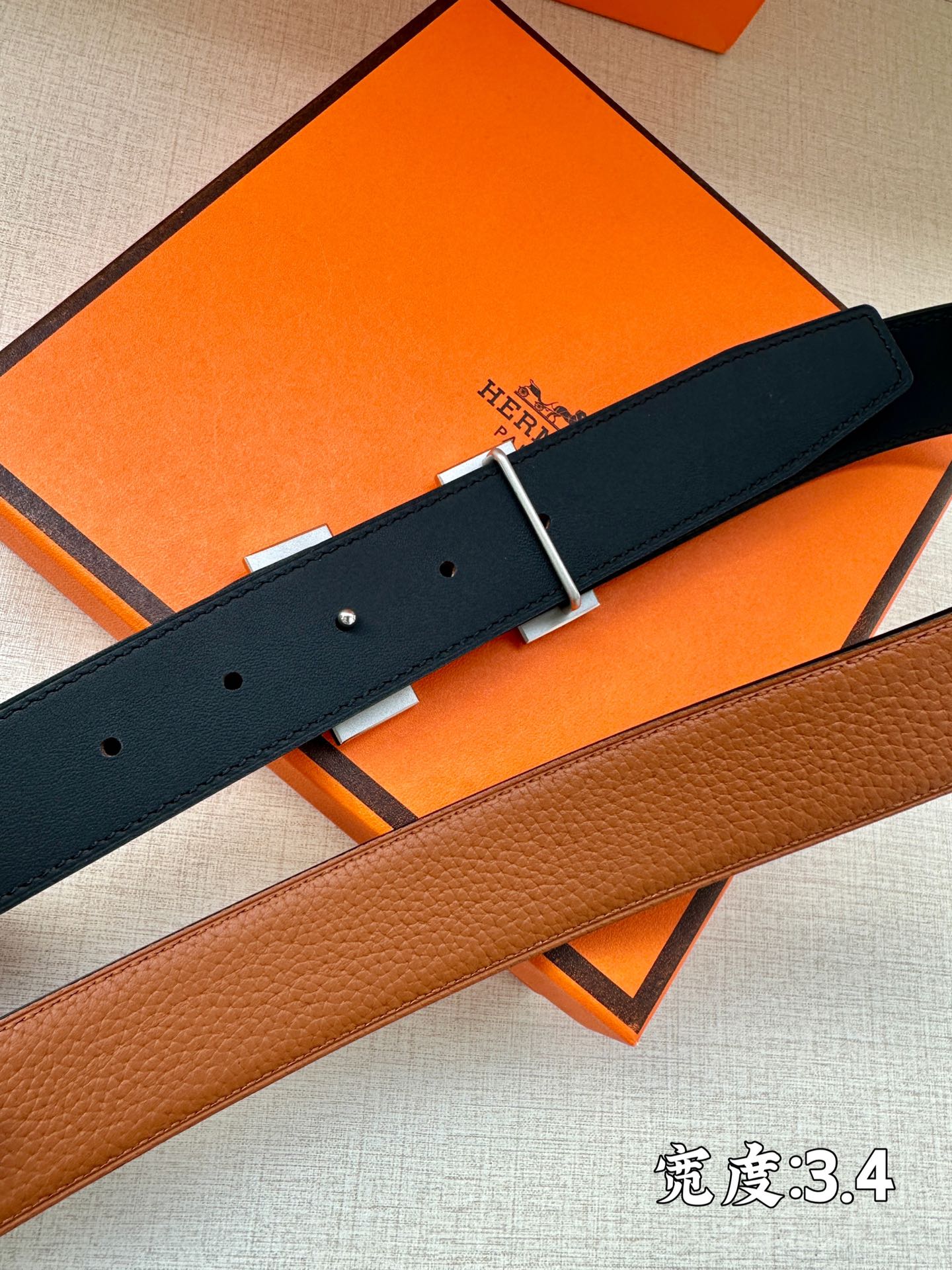 Navy leather belt with silver H buckle, close-up of holes
