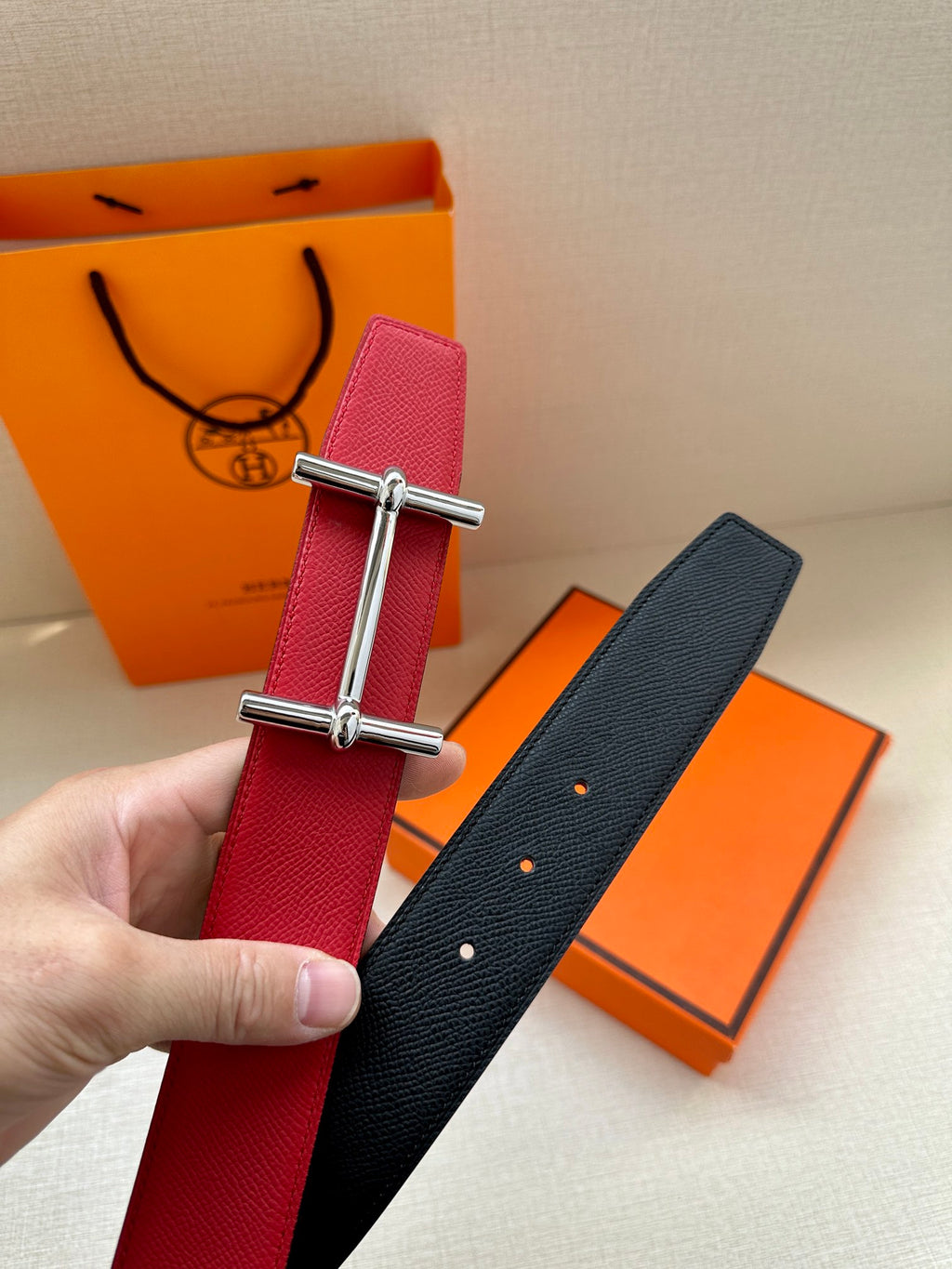 Red leather belt with silver-toned buckle; black leather strap with stud detailing.