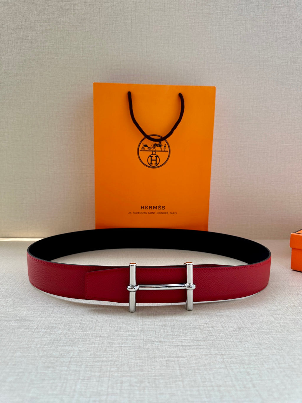 Red leather belt with dark backing and silver-toned buckle, centered on surface.