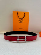 Red leather belt with dark backing and silver-toned buckle, centered on surface.