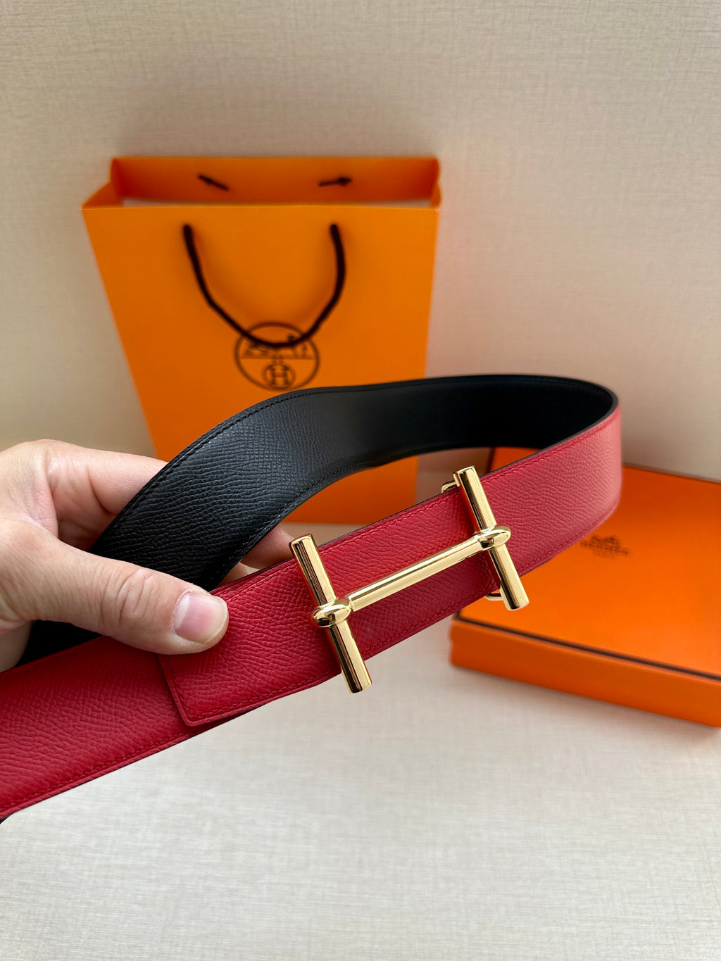 Reversible belt with black and red leather straps and gold-tone double-prong buckle.