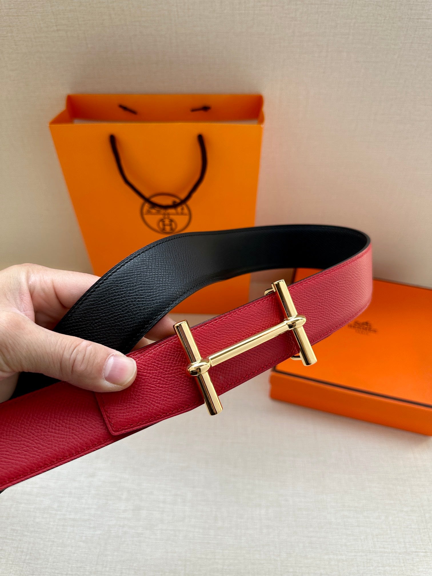 Reversible belt with black and red leather straps and gold-tone double-prong buckle.