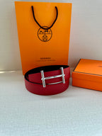 Red leather belt with silver-toned rectangular buckle, laid flat.
